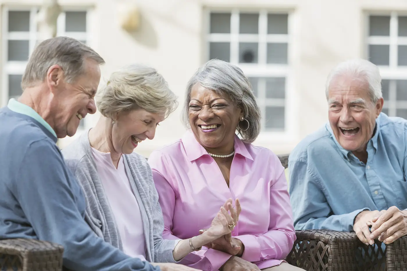 iStock-531609680 A group of four Winnwood residents sit together outdoors, laughing heartily and enjoying conversation in an Independent Living community environment.